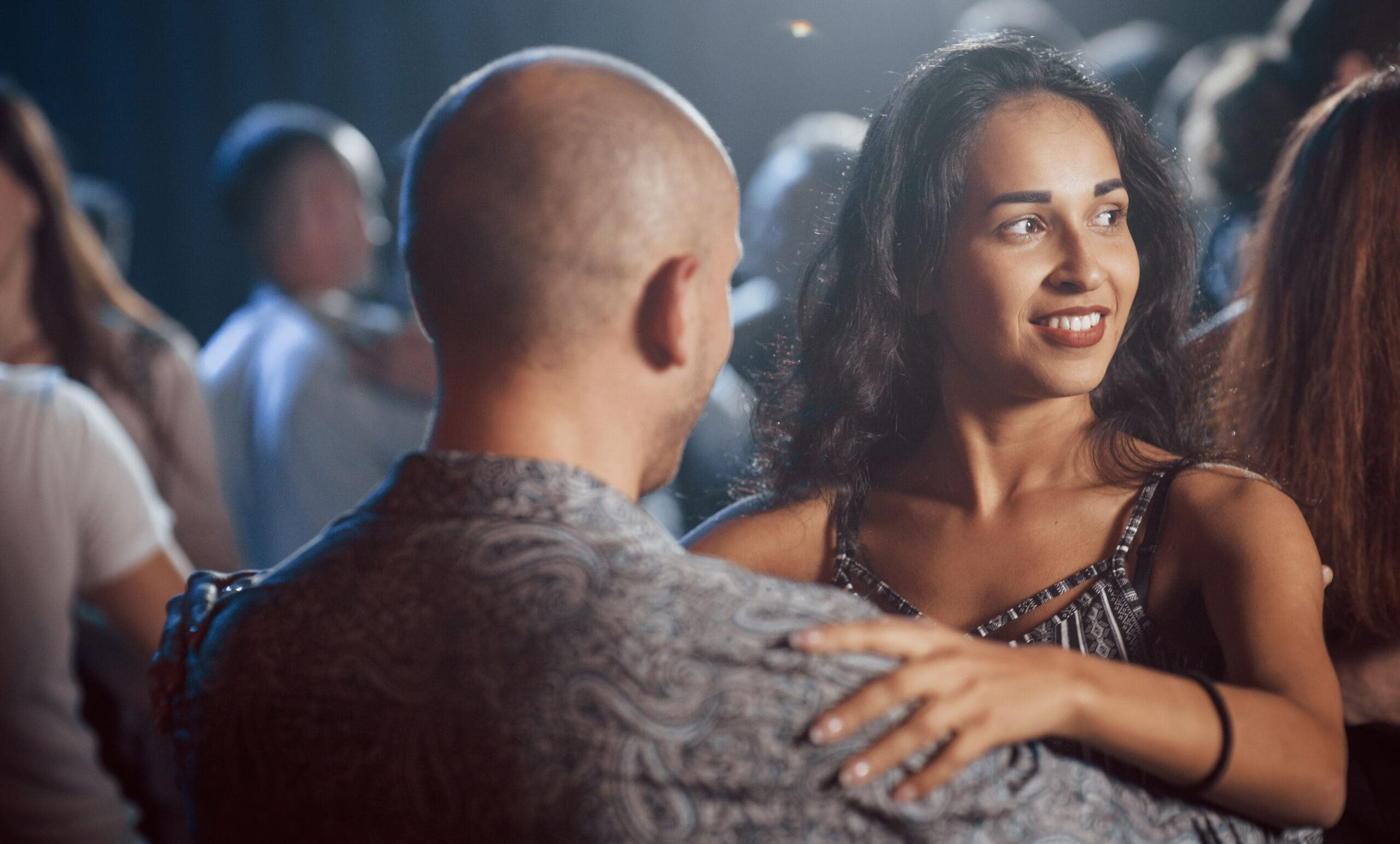 Many of people around. Couple dancing at nightime in the club. Enjoying music and each other.