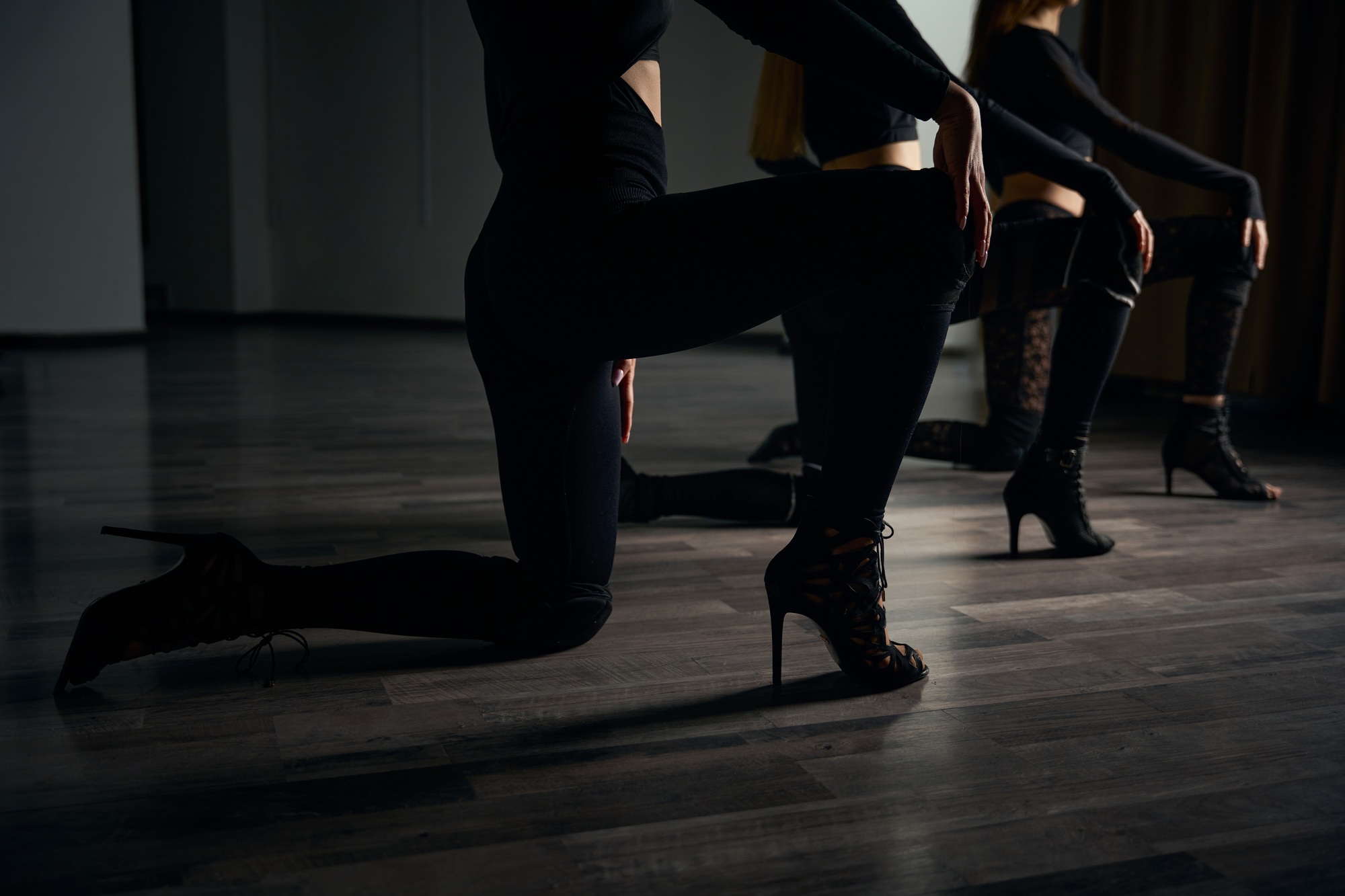 Trio of high heels dancers stretching before dancing